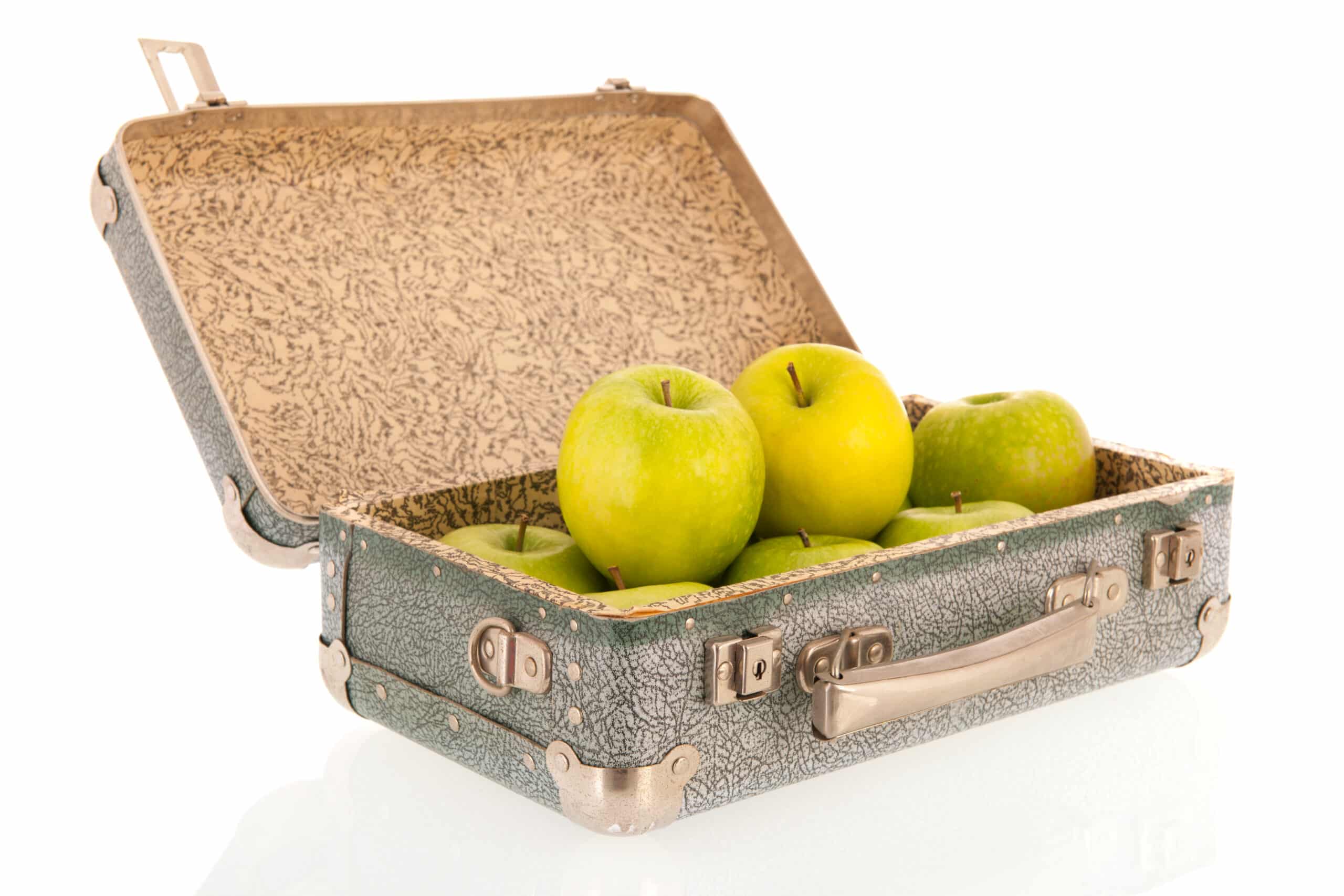 Can I pack food in my checked luggage? Vintage open carton suitcase filled with apples isolated over white background