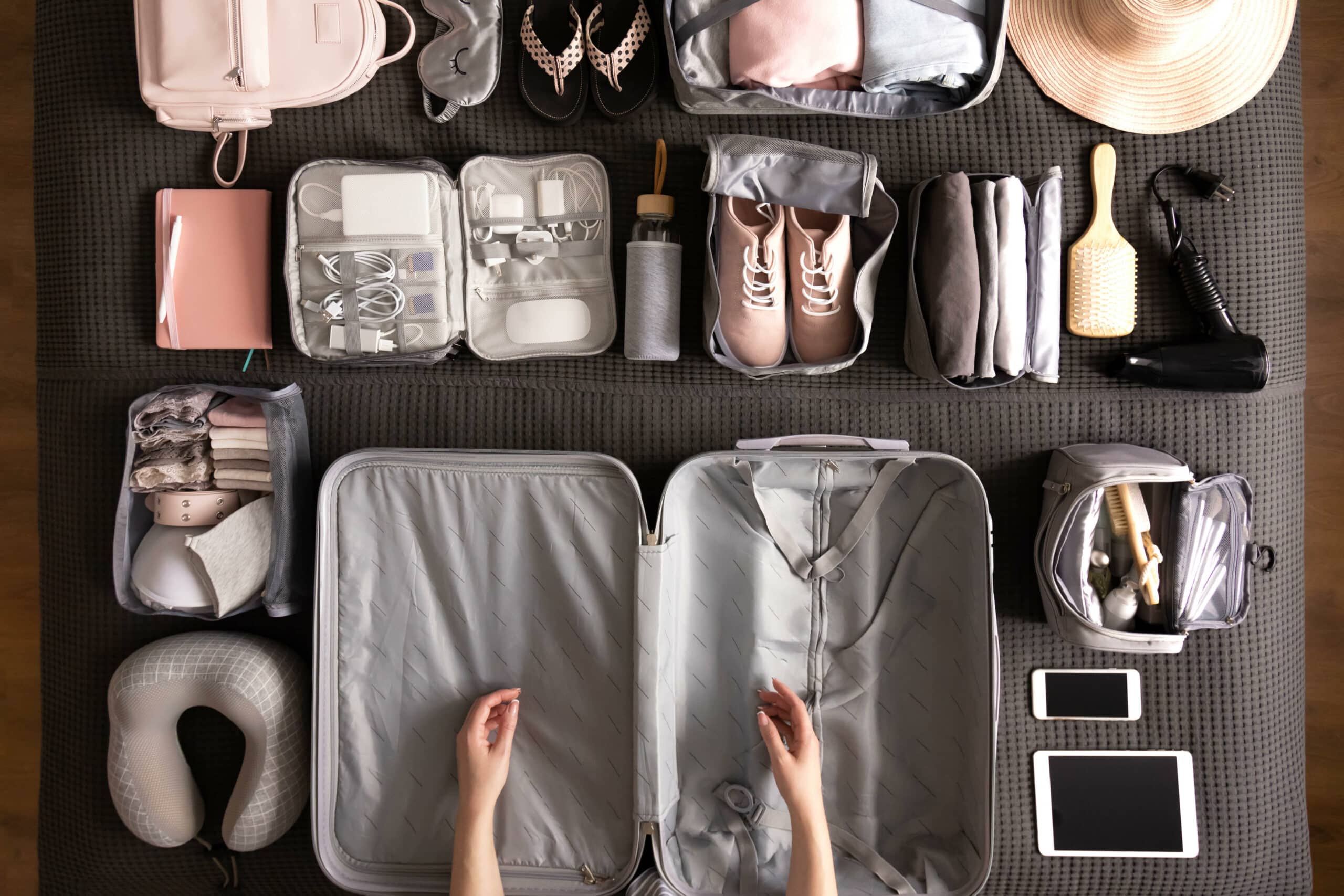 Top view woman hands getting ready to travel vacation packing suitcase with comfortable storage cases use konmari method. Female preparing to journey neatly collecting clothes, cosmetics and technique