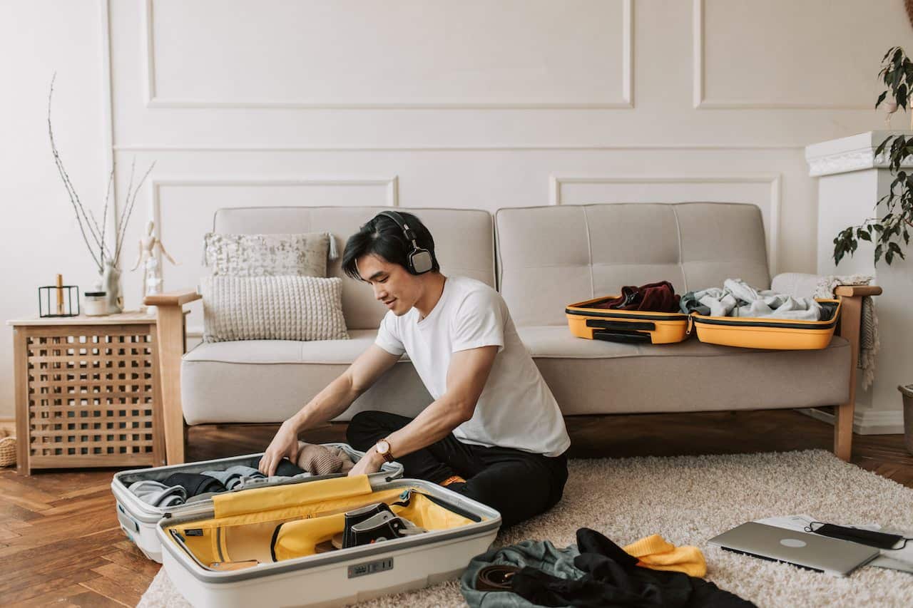 man packing luggage in living room