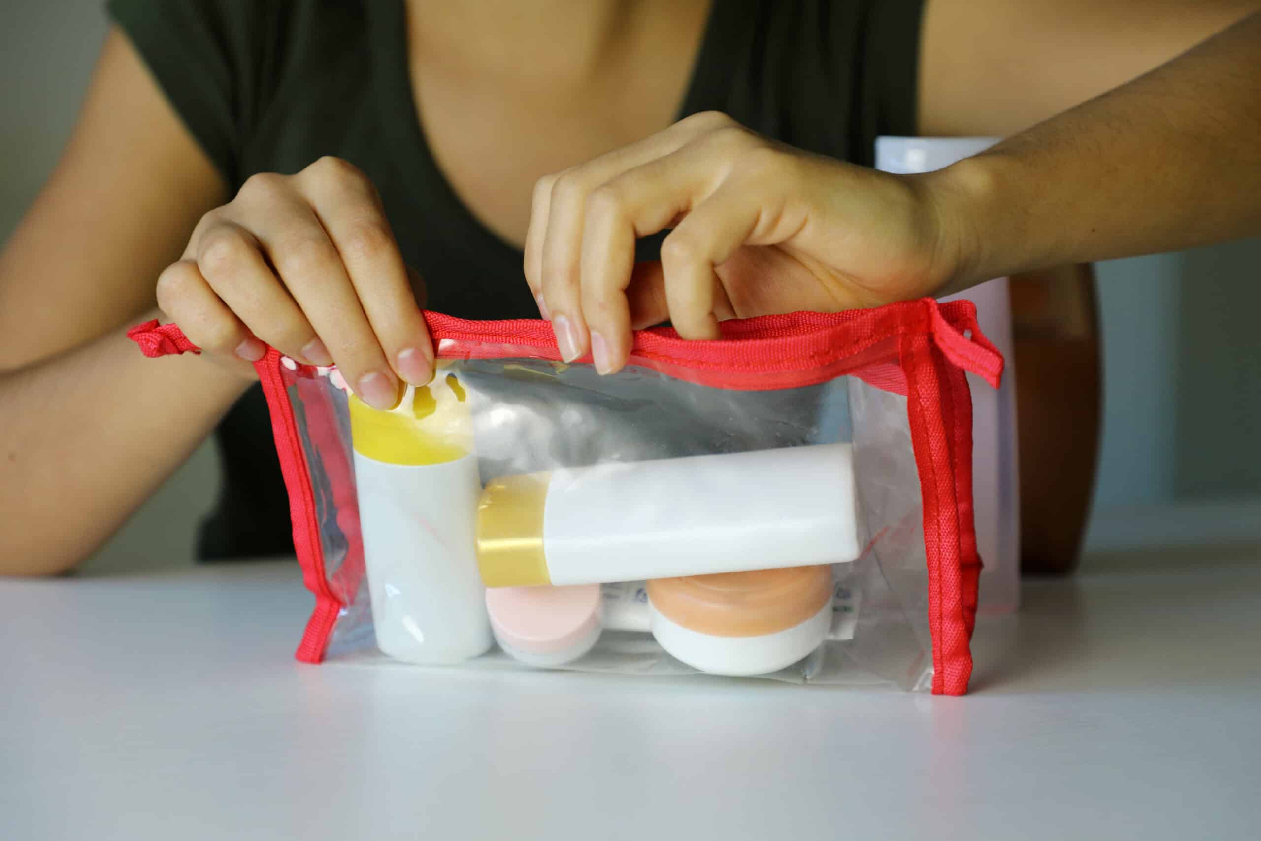 woman filling quart-sized bag with toiletries