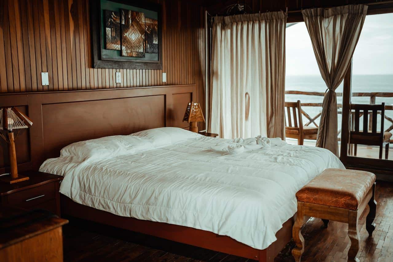 Rustic luxury hotel room by the ocean with a balcony.
