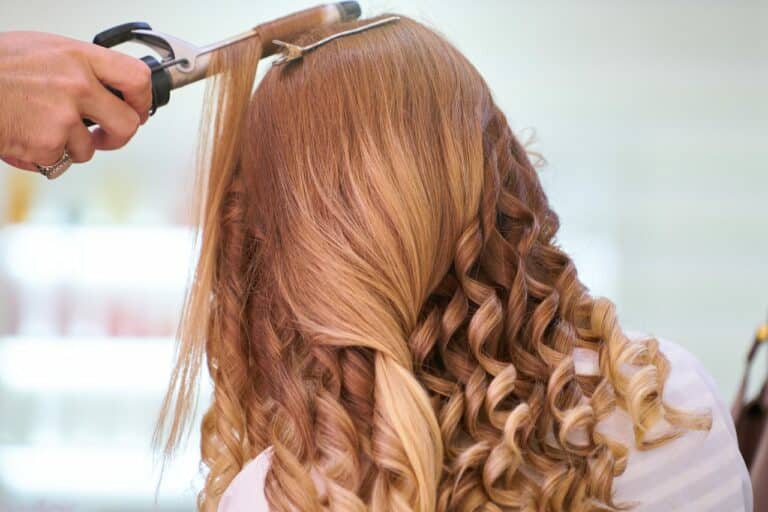 curling iron being used on woman with red hair