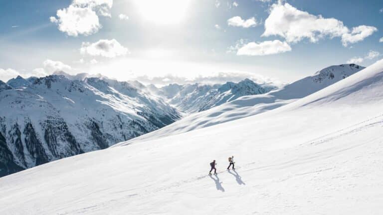 2 people climbing snowy hill