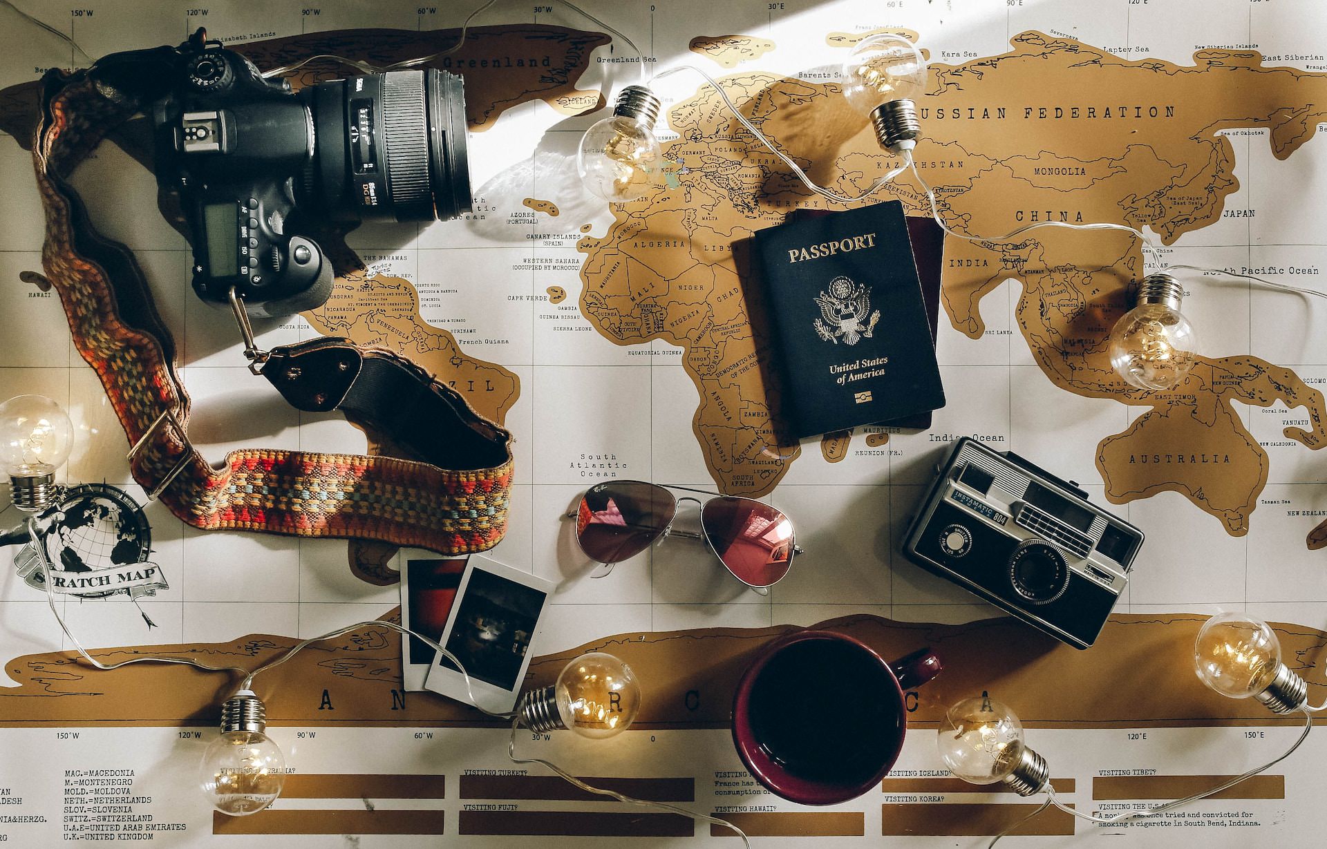 World map with passport, DSLR, and sunglasses on top of it. Is there travel insurance similar to World Nomads?